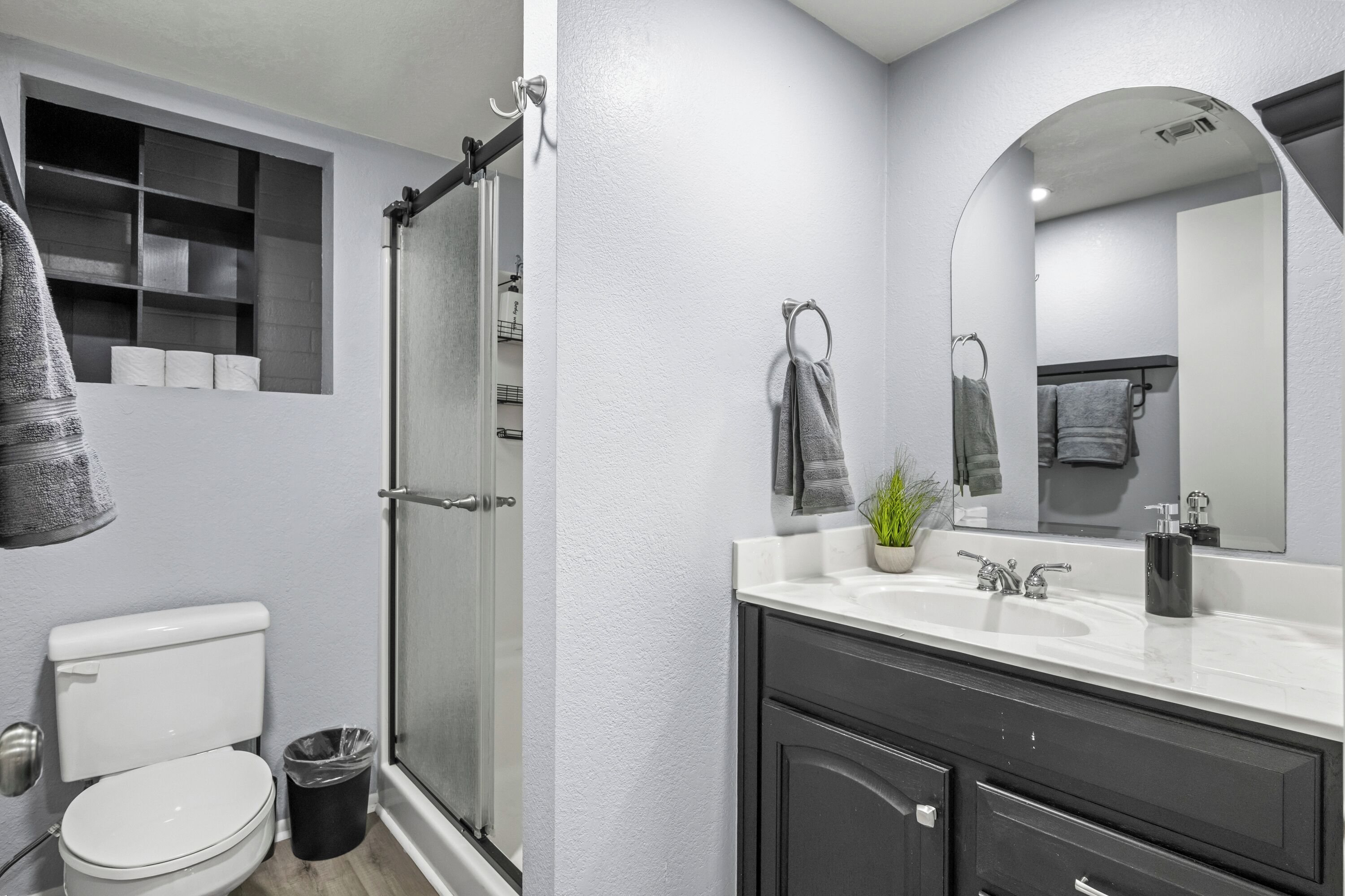 A modern bathroom with a toilet, shower, and vanity with a sink and mirror.