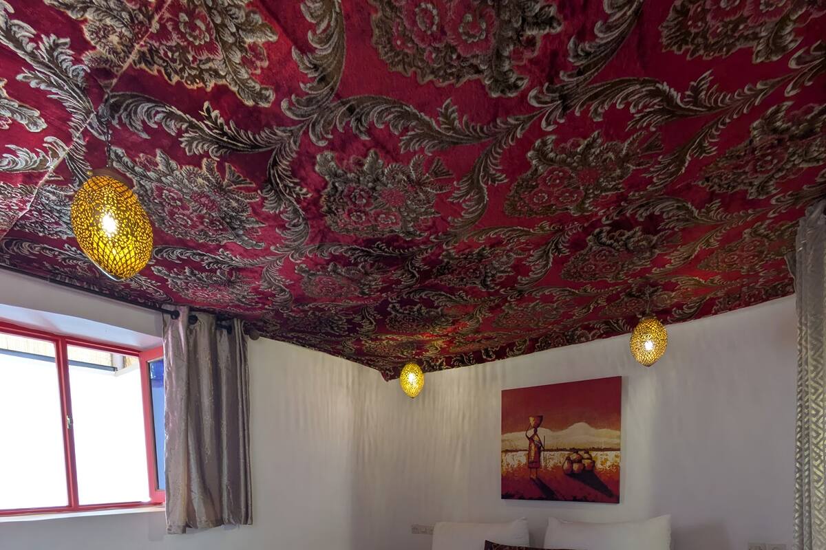 A hotel room with a large bed, patterned carpet, and a ceiling with intricate designs.