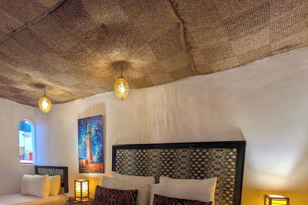 A hotel room with a large bed, two bedside tables, a patterned rug, and a painting of a tower.