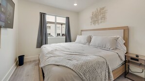 A bedroom with a bed, a nightstand, a window with curtains, and a wall-mounted artwork. - Stylish City Getaway | Near Deep Ellum & Downtown (Dallas)