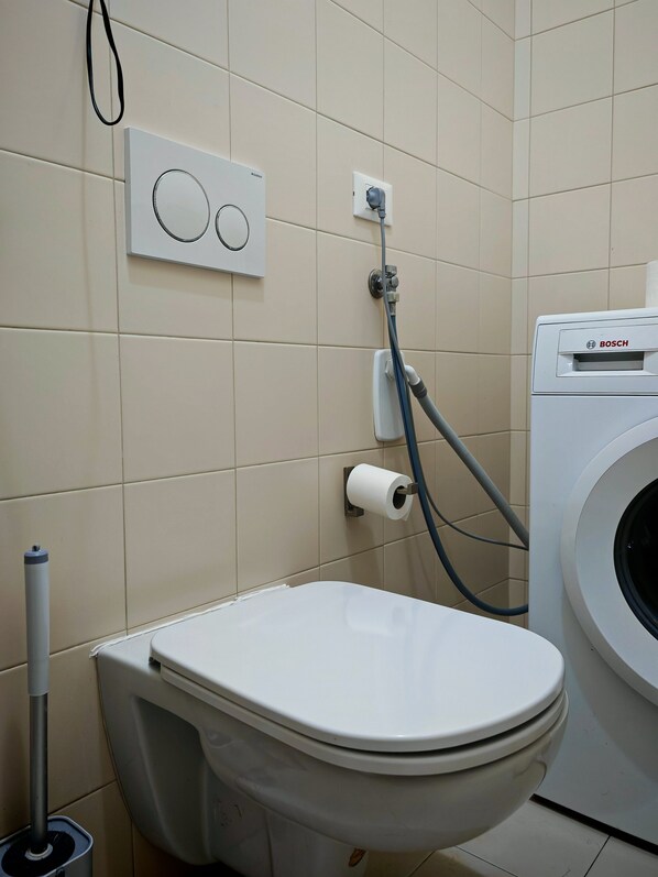 Une salle de bain équipée de toilettes, d’un lave-linge et d’un sèche-mains.