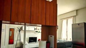 A compact kitchen with wooden cabinets, a marble countertop, a built-in TV, and a refrigerator. - Charming Apartment with Garden View in enchanting Venezia (Sestiere Cannaregio)