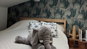 Un dormitorio con tragaluz, una cama con cubrecama acolchado y una pared con diseño de hojas.
