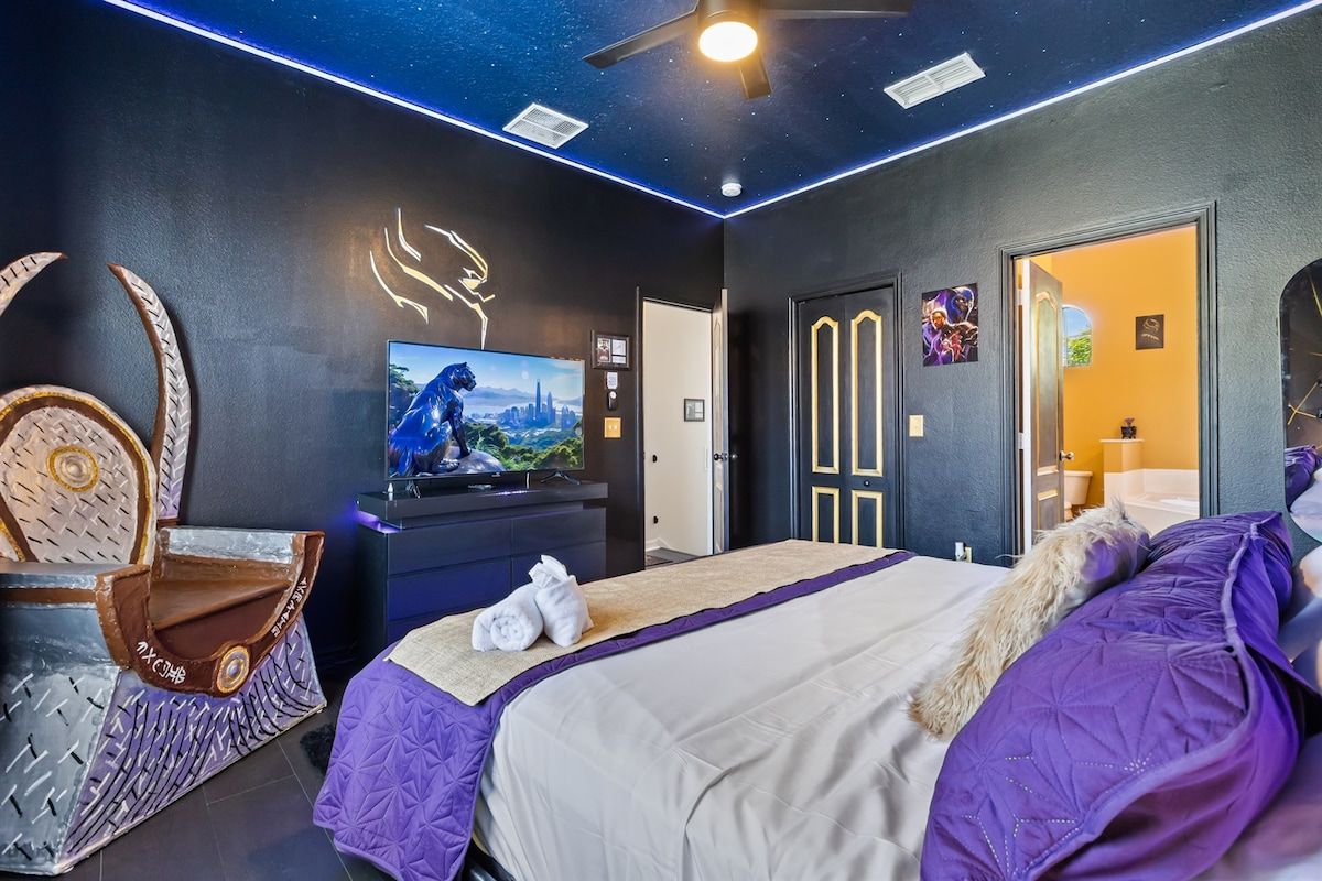 Una habitación de hotel moderna con una cama grande, un televisor y un ventilador de techo.