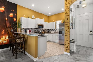 A kitchen with white cabinets, a central island, and a brick accent wall.