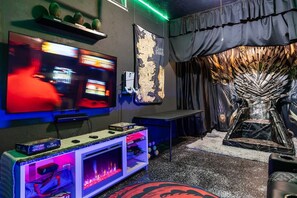 A gaming room with a large TV, gaming console, and a decorative throne-like structure.