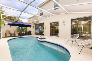 A swimming pool with lounge chairs and a covered patio area.