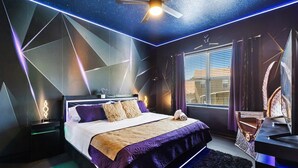 Un dormitorio moderno con cama, mesitas de noche, escritorio y ventilador de techo.