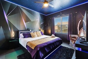 A modern bedroom with a bed, nightstands, a desk, and a ceiling fan.