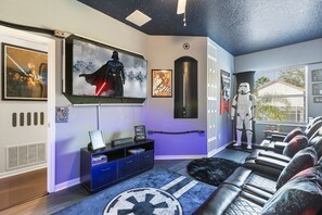 A room with a Star Wars theme, including a Darth Vader poster, a Stormtrooper figure, and a Star Wars-themed rug.