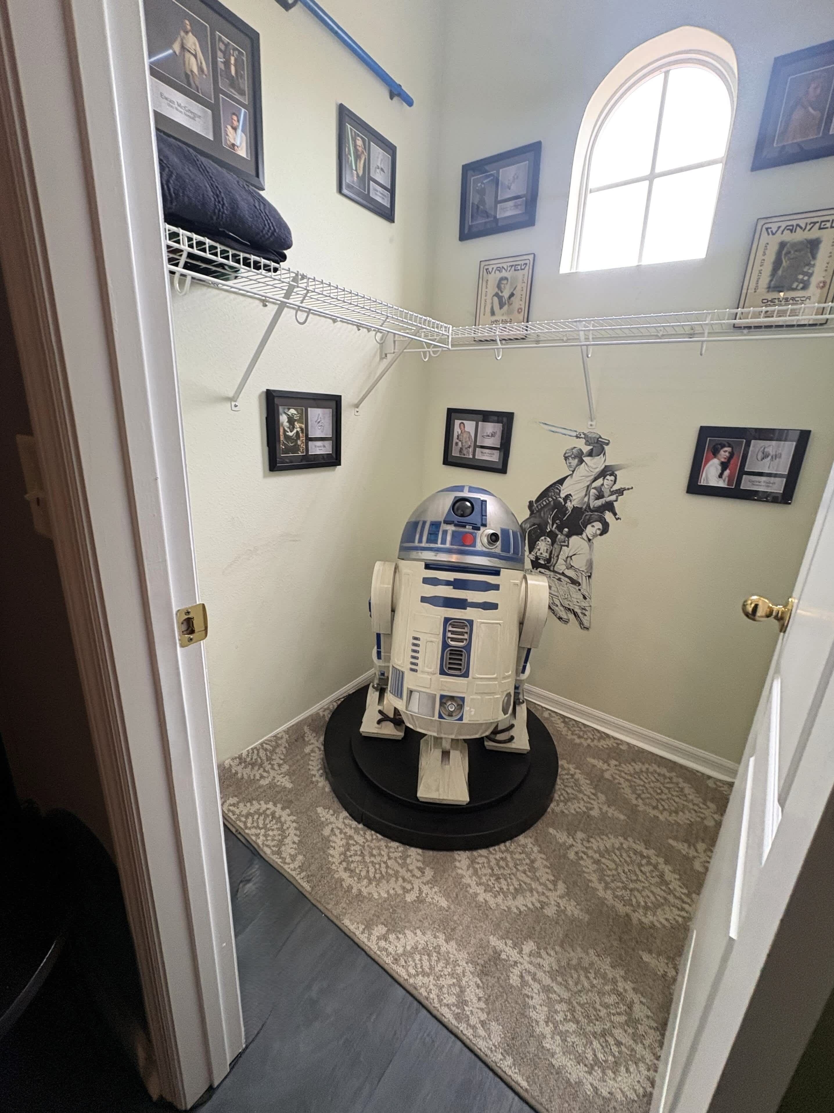 Une salle de bain décorée sur le thème de Star Wars, avec notamment une figurine de R2-D2 sur un présentoir, des tableaux encadrés aux murs et une fenêtre offrant une vue agréable.