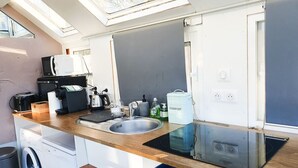 A compact kitchen with a sink, a coffee maker, a toaster, and a compost bin.