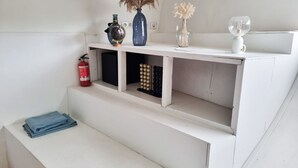 A white shelf with decorative items and a fire extinguisher.