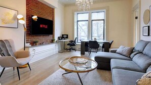 A modern living room with a fireplace, a TV, a dining area, and a large window.