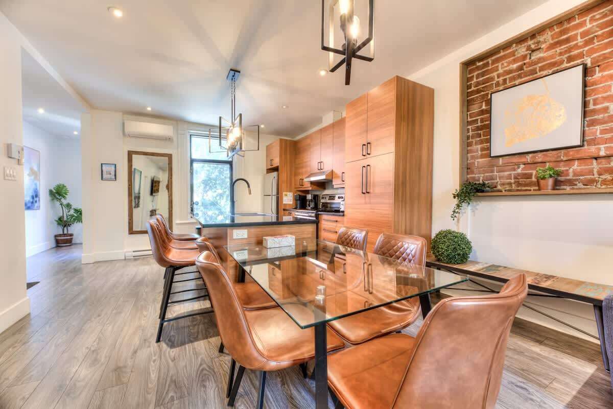 A modern kitchen with wooden cabinets, a glass dining table, and leather chairs.