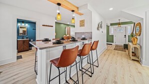 A modern kitchen with a central island, bar stools, pendant lighting, and a wooden ceiling beam. - Lakeview Modern Stay Near Beaches, GOTL, and Spire (Ashtabula)