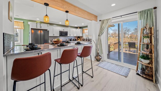 A modern kitchen with a central island, bar stools, and a view to an outdoor deck. - Lakeview Modern Stay Near Beaches, GOTL, and Spire (Ashtabula)