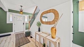 A modern interior with a staircase, a wooden console table, a mirror, and a potted plant. - Lakeview Modern Stay Near Beaches, GOTL, and Spire (Ashtabula)