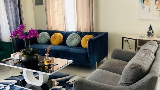 Un soggiorno moderno con un divano blu, una poltrona grigia e un tavolino da caffè con oggetti decorativi.
