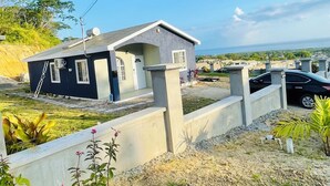 Un edificio residenziale con vialetto in cemento, un garage e vista sul mare.