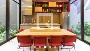 Een moderne keuken met een houten aanrechtblad, rode stoelen en een inbouwplank met planten.