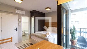 Hotelkamer met een bed, een houten tafel, een kamerplant en uitzicht op buiten.