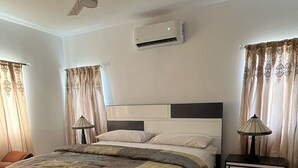 Un dormitorio moderno con cama, mesitas de noche, aire acondicionado y ventilador de techo.
