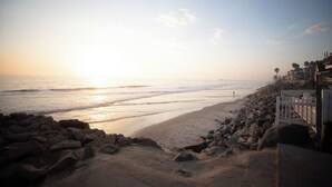 Ein Strand mit felsigem Ufer und einem weißen Zaun.