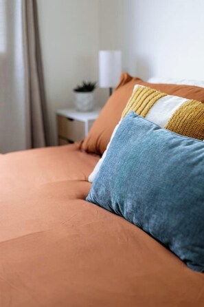A bed with a single blue pillow and a yellow and white striped pillow.