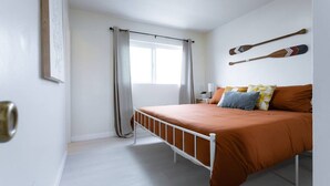 Ein Schlafzimmer mit einem Einzelbett, einem Fenster mit Vorhängen, einem Nachttisch mit Lampe und zwei Schlägern an der Wand.