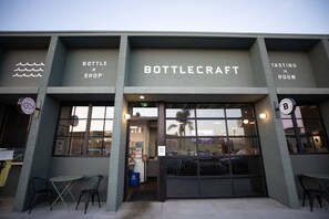 A building with a storefront labeled 'BOTTLECRAFT' and a sign indicating a 'TASTING ROOM' on the right.