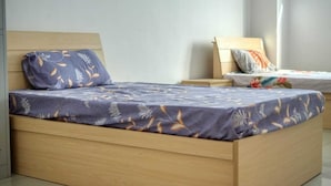 Ein Einzelbett mit Holzrahmen und einem zudeckenden Bettbezug mit Blumenmuster.