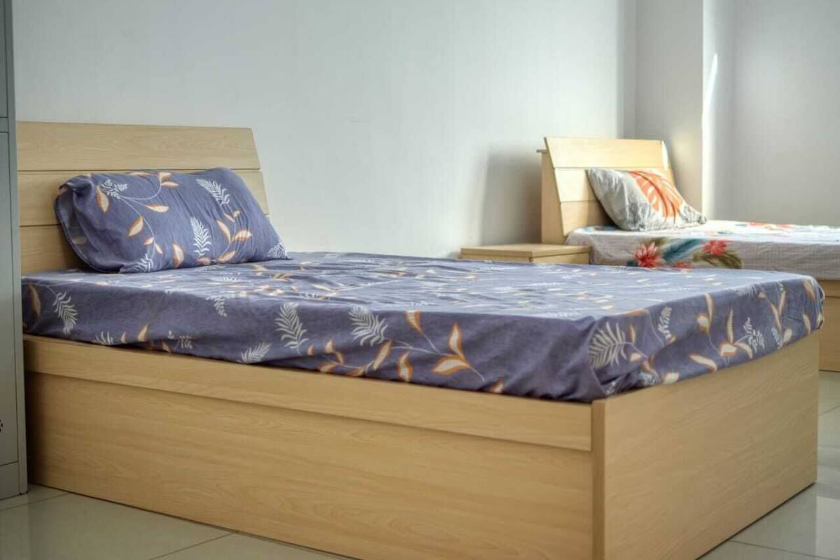 A single bed with a wooden frame and a floral-patterned bedspread.