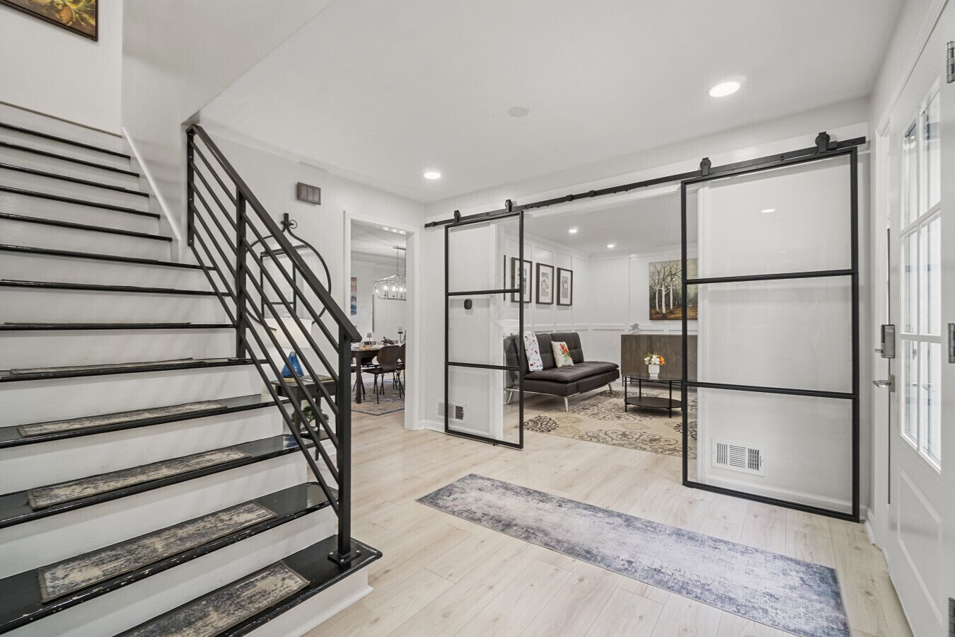 Un intérieur moderne comprenant un escalier, un coin repas et un espace salon avec un canapé et une table basse.
