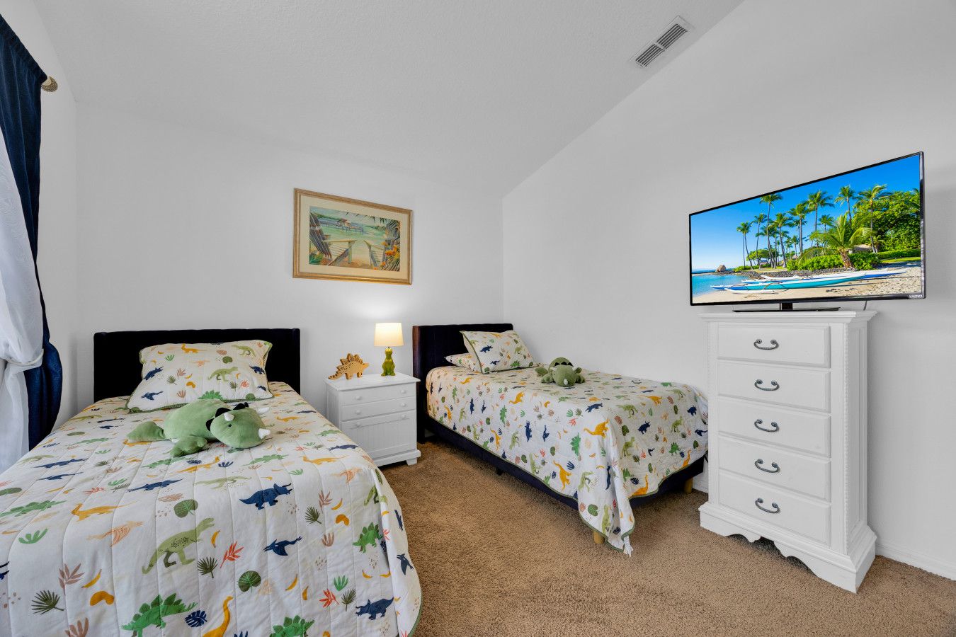 Une chambre avec deux lits, une table de chevet, une commode, un téléviseur et un tableau au mur.