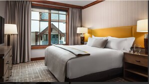 Ein Hotelzimmer mit einem großen Bett, zwei Nachttischlampen, einem Nachttisch, einer Kommode und einem Fenster mit Vorhängen.