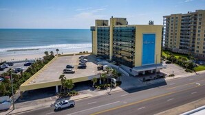 Un hôtel doté d’un parking, offrant une vue sur la plage et comprenant un grand bâtiment avec une porte bleue.