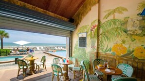 Un restaurant situé en bord de mer, doté d’une terrasse, d’une piscine et d’une fresque représentant un paysage tropical.