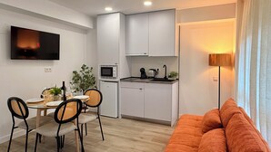 Un appartamento moderno con zona pranzo, angolo cottura e soggiorno con divano.