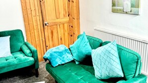 Una habitación con un sofá verde, un sillón verde y una puerta de madera.