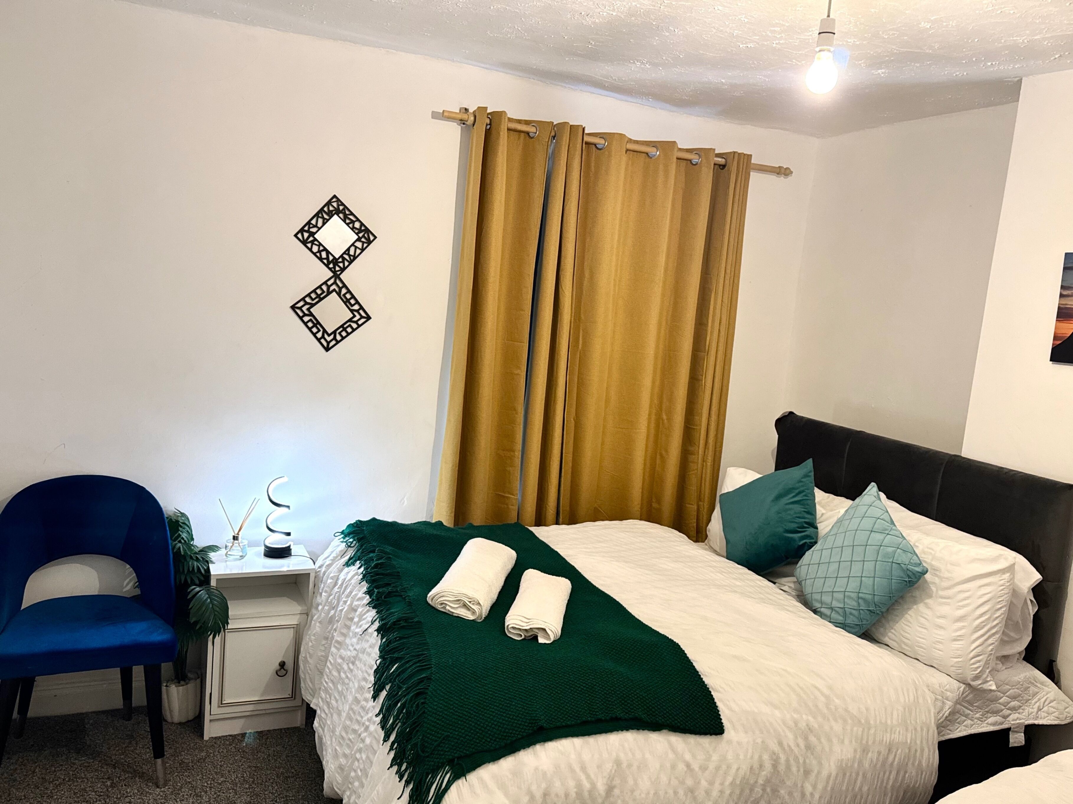 A neatly arranged bedroom with a bed, a chair, a bedside table, and a wall decoration.