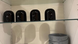 Una estantería con cuatro recipientes negros y uno gris.