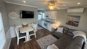 A compact living space with a dining area, kitchenette, and a sofa.