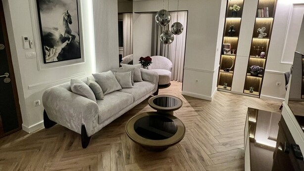 A modern living room with a sofa, a coffee table, and a decorative mirror.