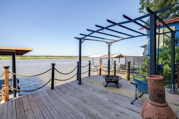 A wooden deck with a pergola, a rope barrier, and a rustic clay pot.