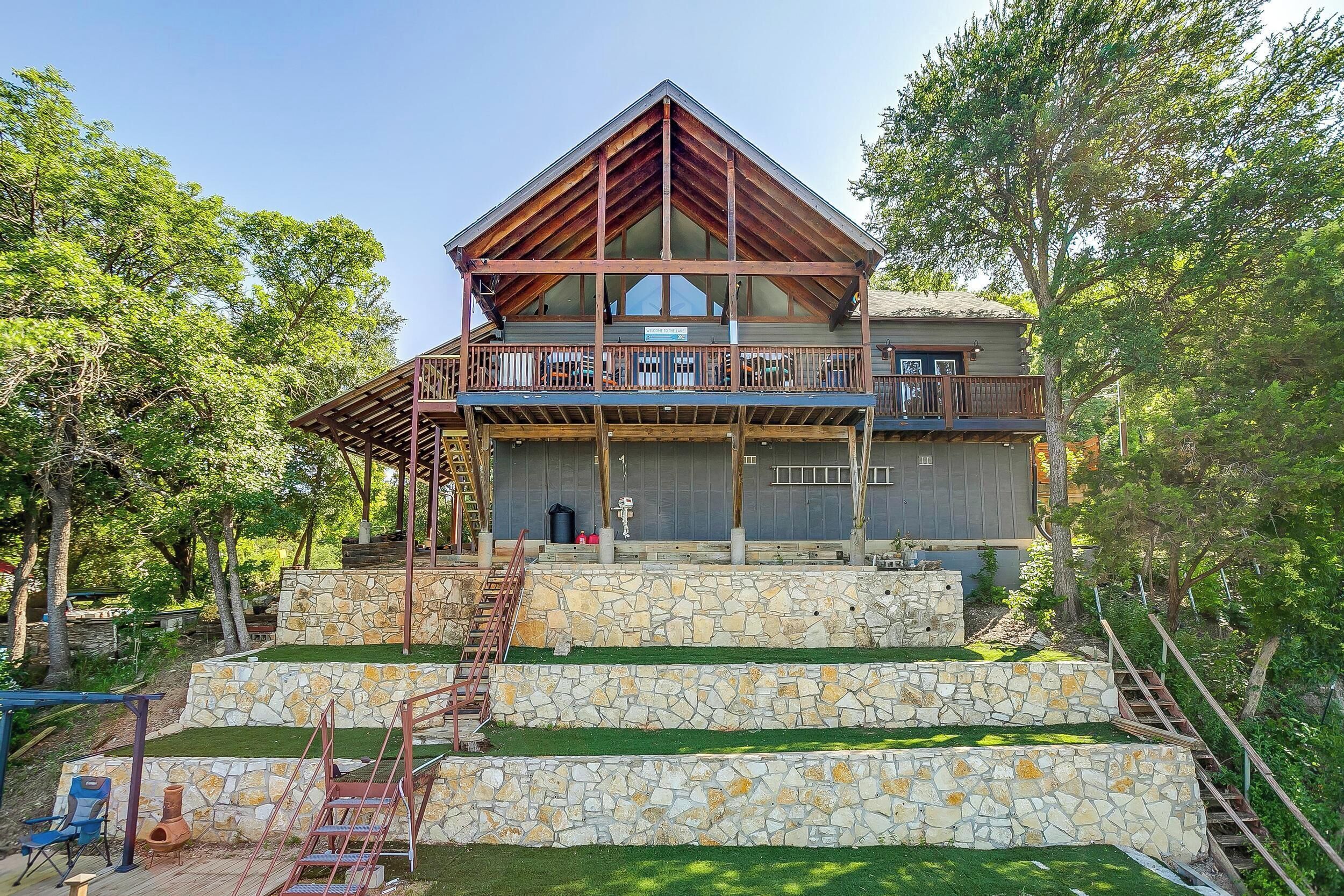 Un bâtiment à deux étages doté d’un escalier en pierre, d’une terrasse en bois et d’un balcon.