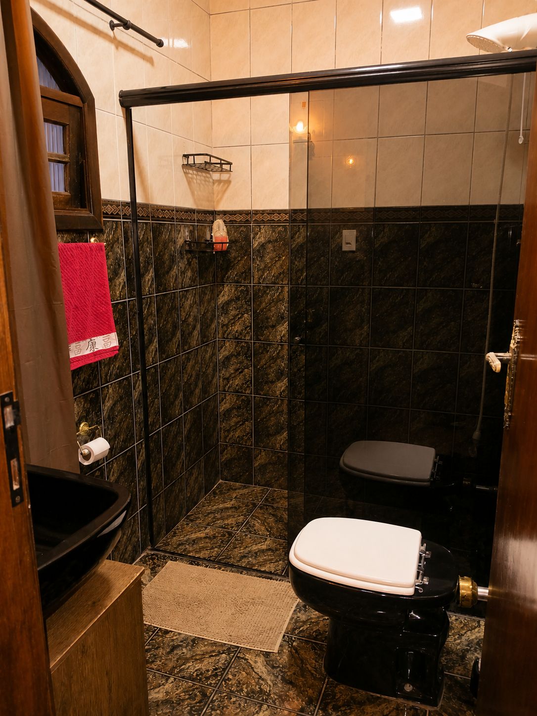 Een kleine badkamer met toilet, douche en een wastafeltje.