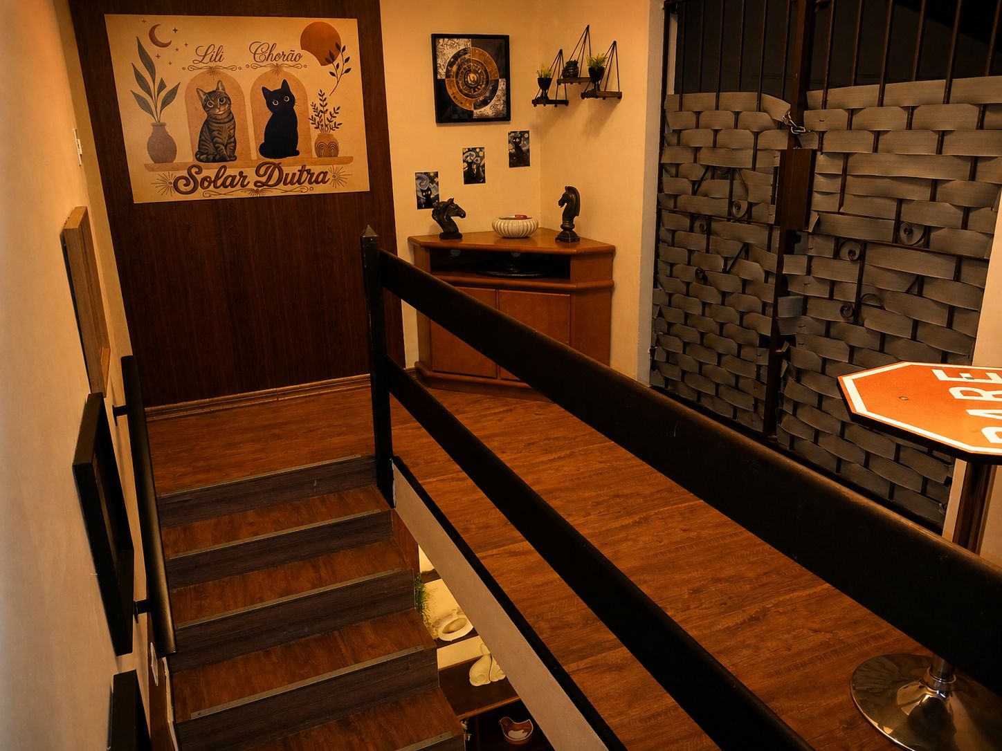 Een trap met een houten leuning en een zwarte balustrade, die leidt naar een ruimte met een bakstenen muur en een bord waarop 'BAR' staat.