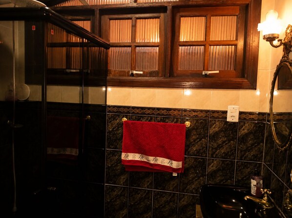 A bathroom with a red towel hanging on a rack, a black bathtub, and a window with curtains.