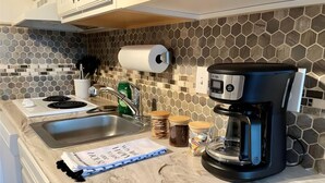 Une cuisine dotée d’un plan de travail en marbre, d’une machine à café, d’un rouleau d’essuie-tout, de bocaux et d’un évier.